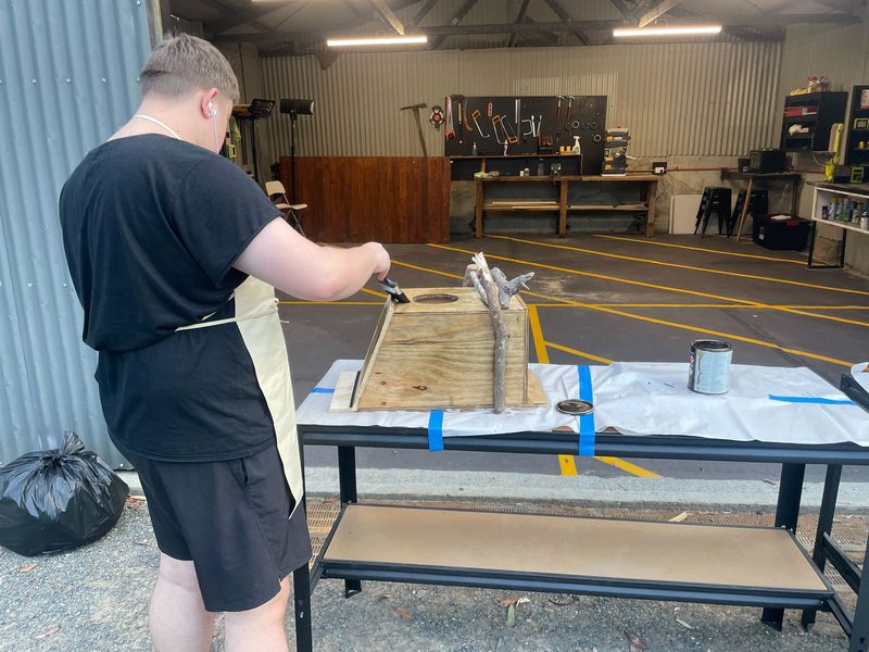 Painting a plywood planter box outside the workshop