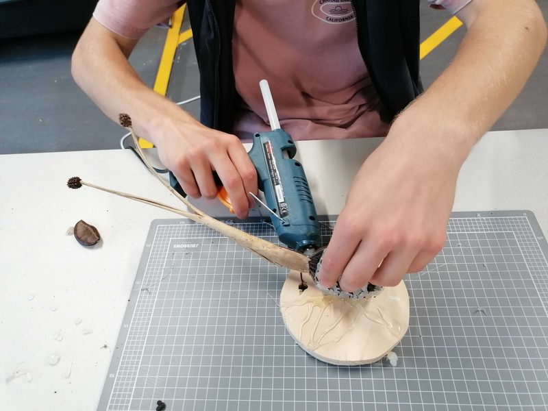 Hands building a craft insect with a glue gun