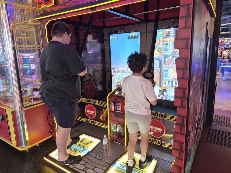 Two people playing side by side at an arcade cabinet