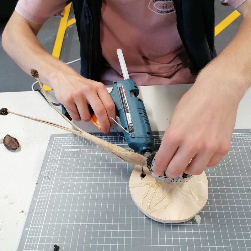 Hands building a craft insect with a glue gun