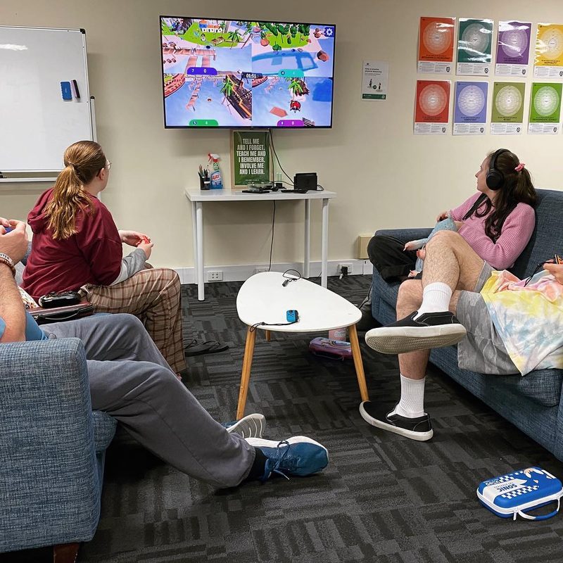 Four people on couches playing a console game