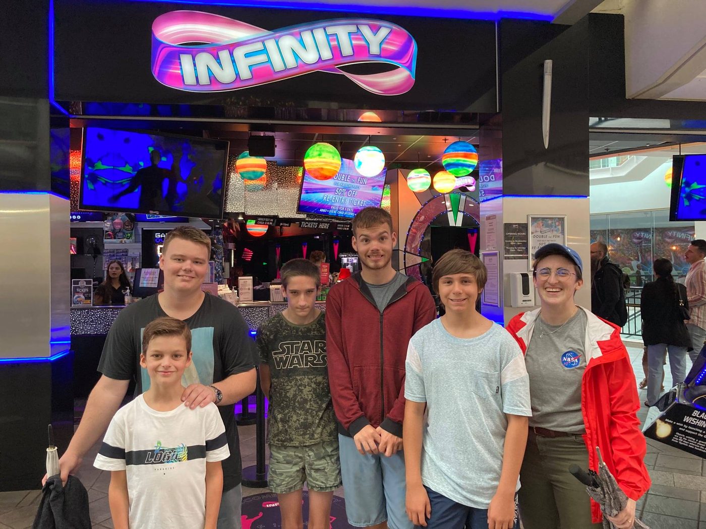 The group together in a neon arcade