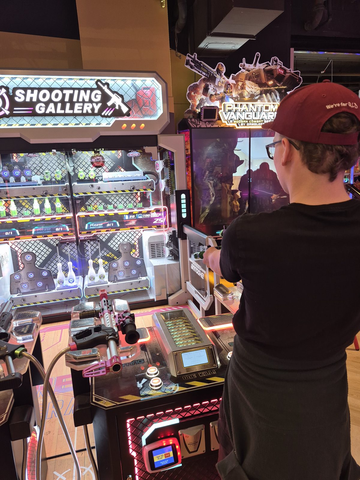 A young person at an arcade shooting game with their support worker