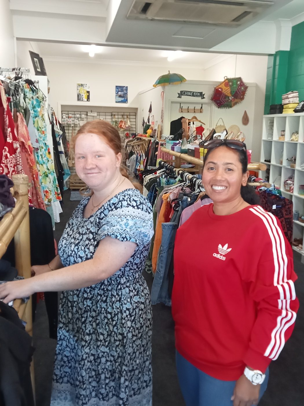A support worker and a participant browsing racks in an op shop